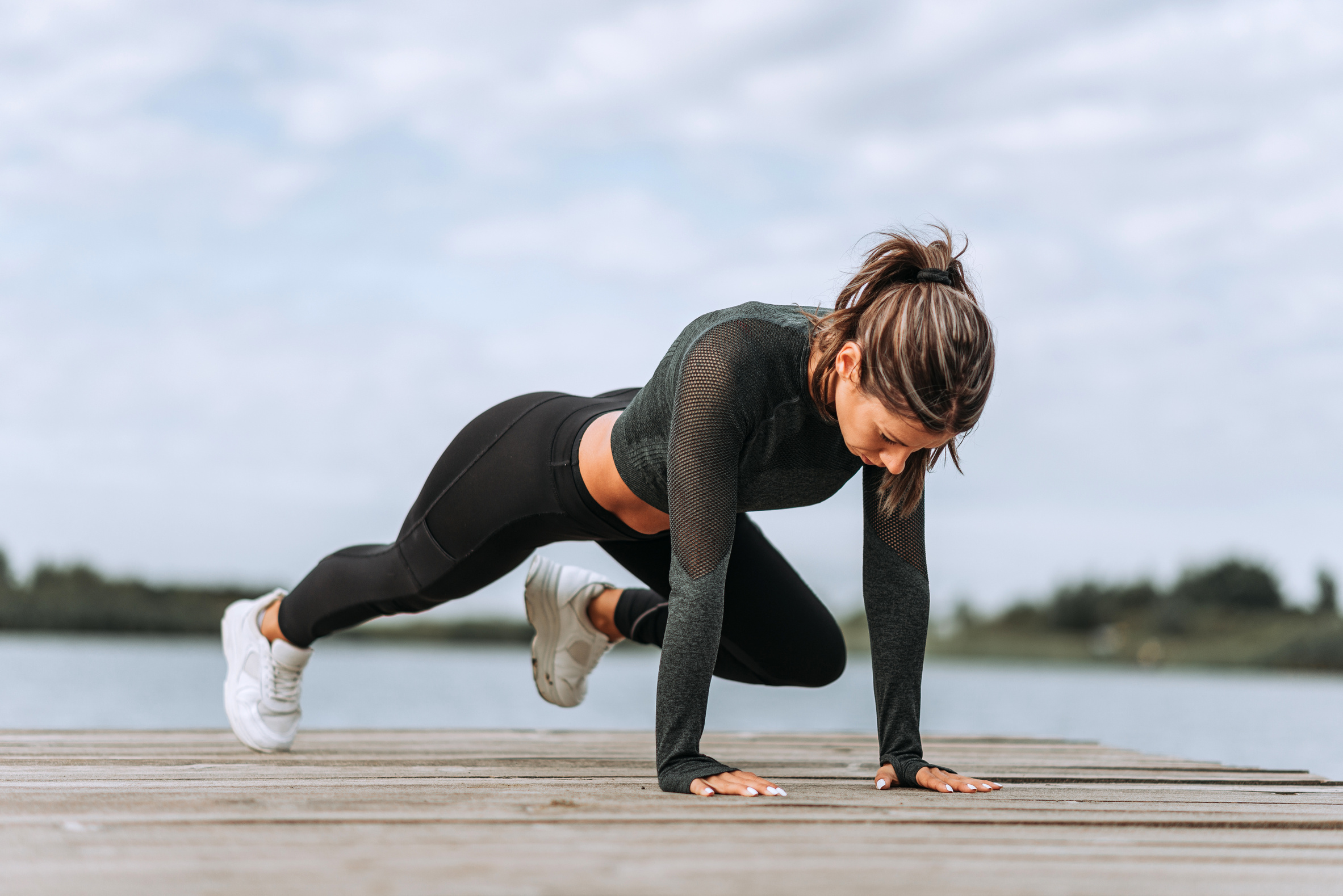 Young fit woman focused on core body workout by the river.